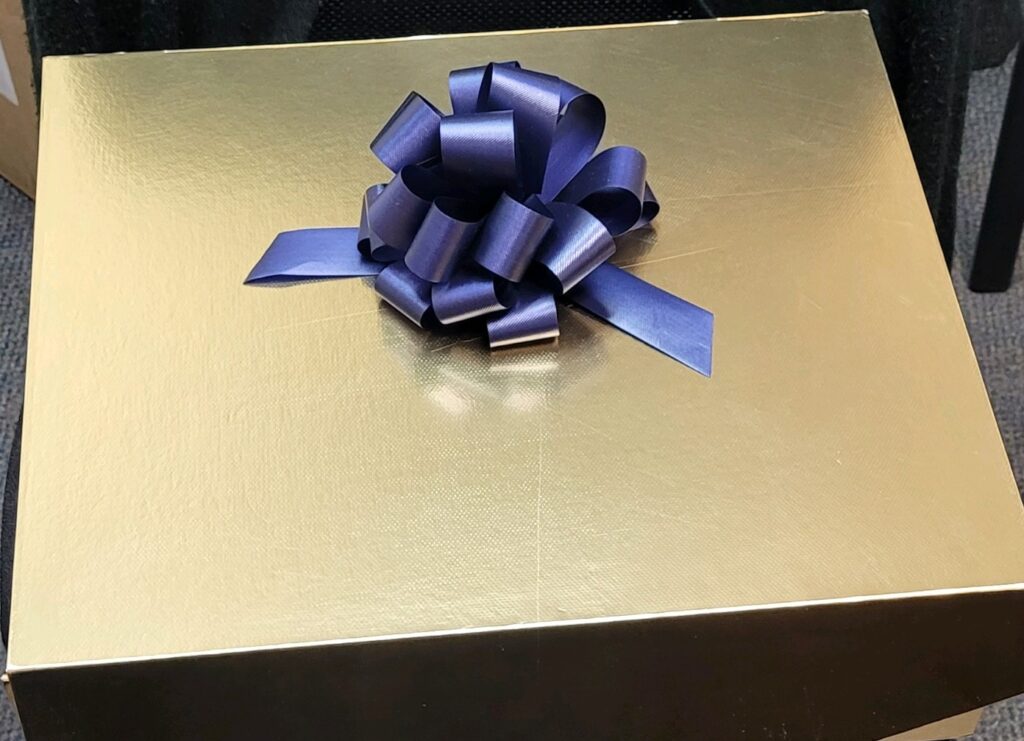 Gold gift box with a big blue bow.